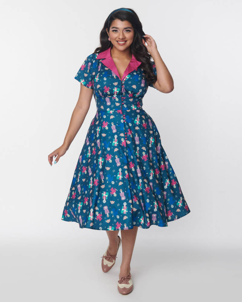 Front of a model wearing a size XL The Golden Girls x Unique Vintage Teal & Pink All Over Print Swing Dress in Teal & Pink Golden Girls Print by Unique Vintage. | dia_product_style_image_id:325117
